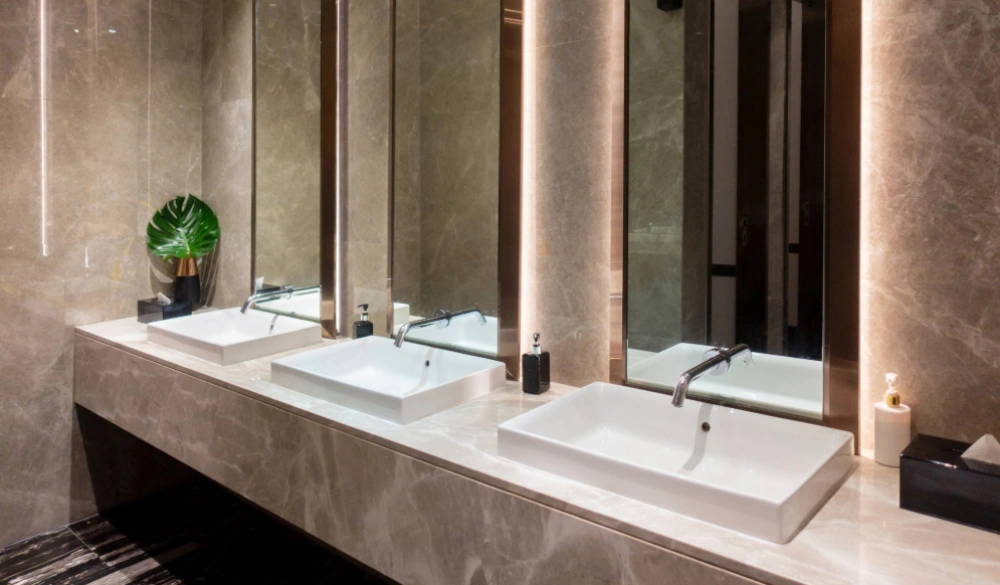 A modern, ceramic office washroom with large, white basins and long mirrors.