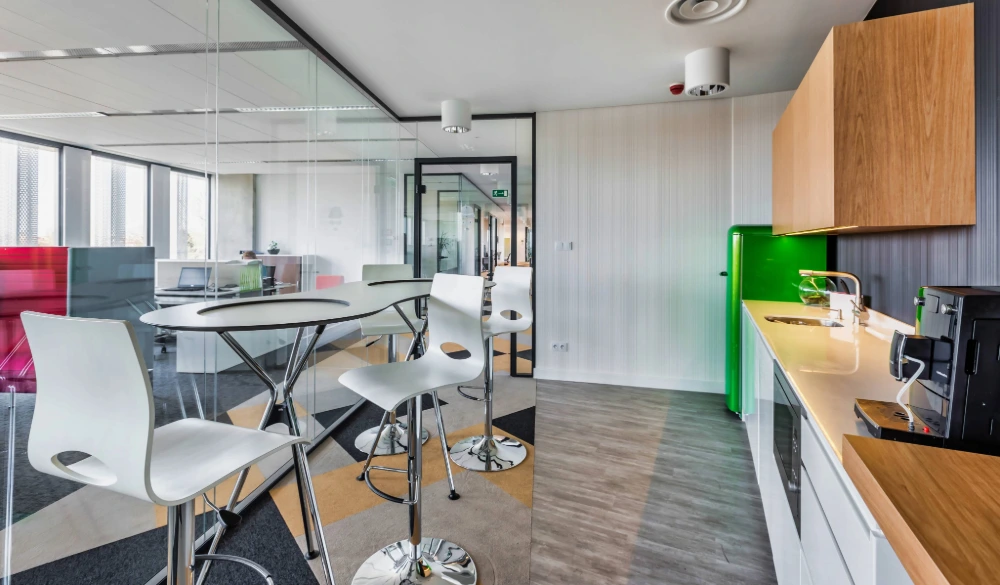 Modern office kitchen with a small table and chairs, a coffee station.