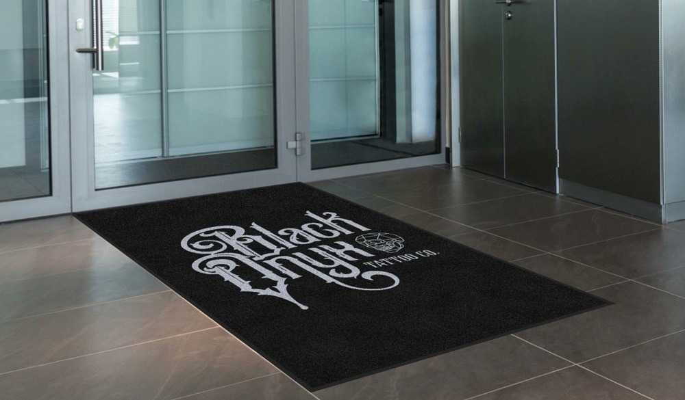 Black heavy duty entrance mat with tattoo studio's logo printed on it. 