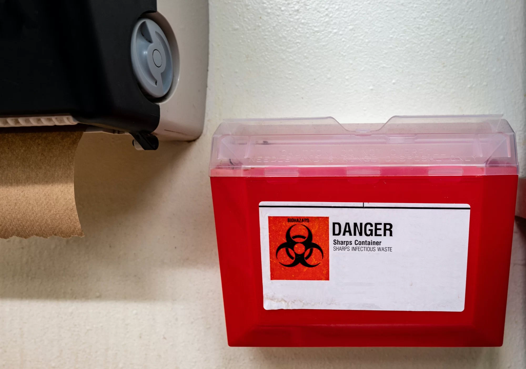 Red biohazard bin for sharps disposal.